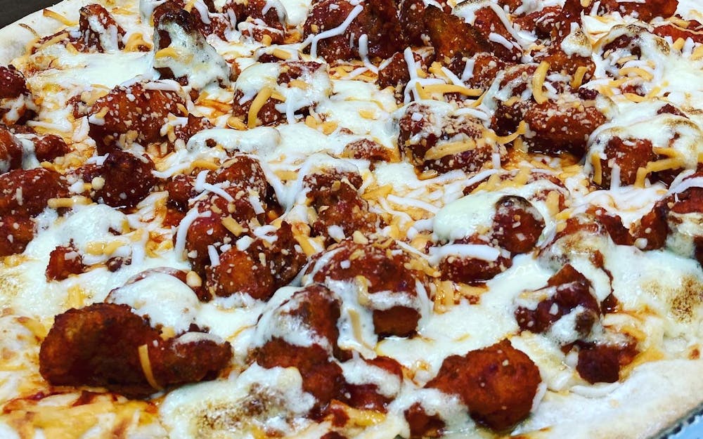 Pizza loaded with saucy fried chicken, melted mozzarella, and a creamy drizzle
